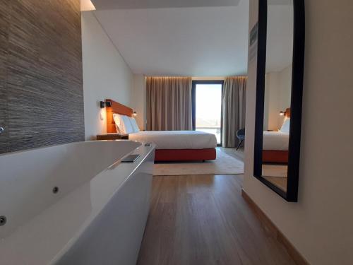 a bathroom with a tub and a bed and a mirror at Casas da Serra - Soeima Housing in Alfândega da Fé