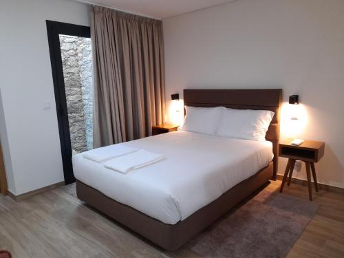 a bedroom with a large white bed with two lamps at Casas da Serra - Soeima Housing in Alfândega da Fé