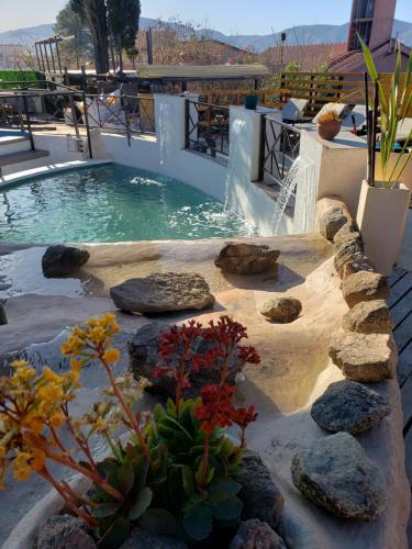 a swimming pool with a waterfall and rocks and a fountain at Complejo Los Cipreses in Villa Carlos Paz