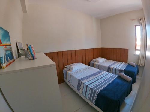 a bedroom with two beds and a desk and a window at Village em Imbassaí in Imbassai