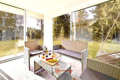 a porch with chairs and a table with fruit on it at Chalet 5 stars in San Bernardino, SKI SLOPES AND HIKING, Fireplace, 4 Snowtubes Free, Wi-Fi Free, for 8 persons, Wonderful in all seasons -By EasyLife Swiss in San Bernardino