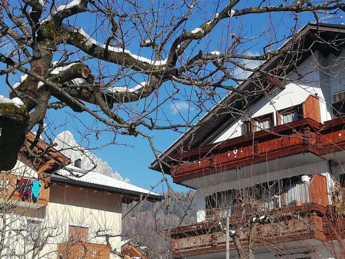 Un uomo è seduto su un albero di fronte a un edificio di La Mansarda di Sabina. a Fiera di Primiero