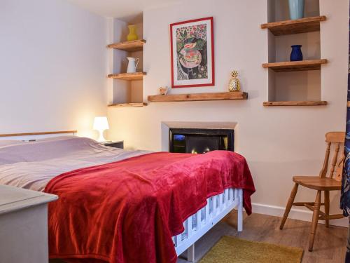 a bedroom with a bed with a red blanket and a fireplace at Ring Of Bells in South Molton