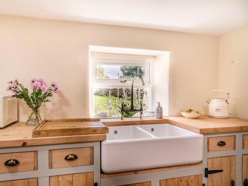 a kitchen with a white sink and a window at Wrens Beck Cottage in Ousby