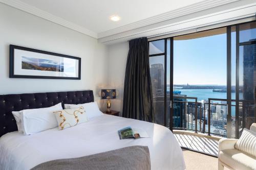 a bedroom with a bed and a large window at Luxury Penthouse Apartment in Auckland