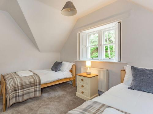 een slaapkamer met 2 bedden en een raam bij East Lodge in Contin