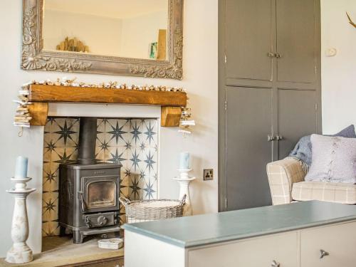 a living room with a fireplace and a stove at Cherrytree Cottage in Chatton