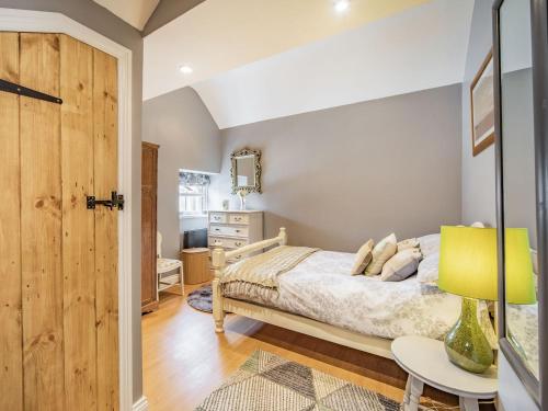 1 dormitorio con 1 cama y 1 mesa con lámpara en Cherrytree Cottage, en Chatton