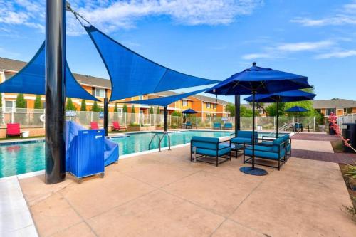 a patio with blue umbrellas and a swimming pool at Sleepover 1BD 1BA Oklahoma City Apartments in Oklahoma City
