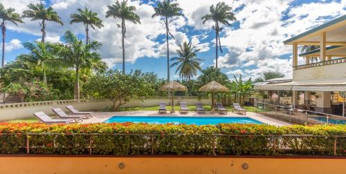 uma piscina num resort com palmeiras ao fundo em Habitation du Comté em Sainte-Rose