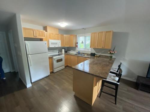 a kitchen with a white refrigerator and wooden cabinets at Kingston Comfort Suites - Unit 2 in Kingston