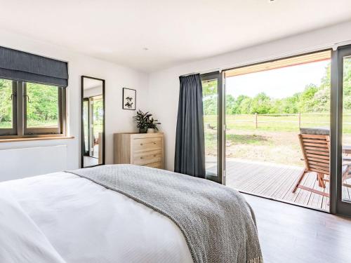een slaapkamer met een bed en een glazen schuifdeur bij Culver Croft in Chiddingstone