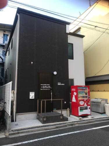 東京にあるLodgingToyko Minowa formerly Hostel HIDEAWAYの赤い扉のある黒い建物