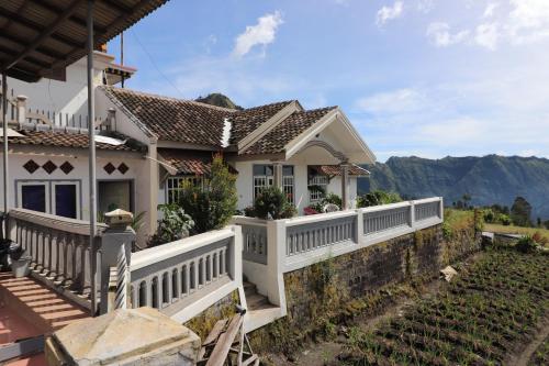 a house with a white fence and mountains in the background at Good Karma Bromo Guesthouse in Bromo