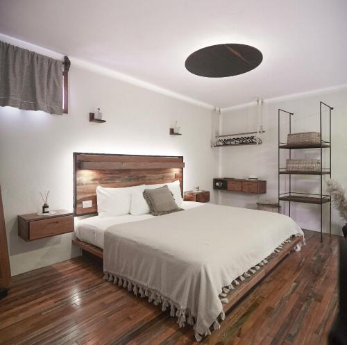 um quarto com uma grande cama branca e pisos em madeira em Hotel Boutique TerraNova em Tulum