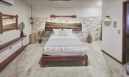 a bedroom with a large bed and a stone wall at Hotel Boutique TerraNova in Tulum