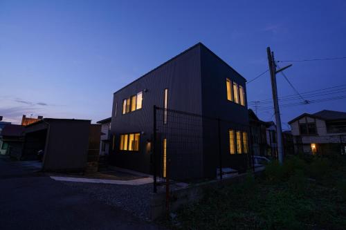 a black house with illuminated windows at dusk at PrimeRoomBeppu SAKURA in Beppu