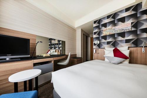 a hotel room with a large bed and a tv at ANA Crowne Plaza Kanazawa by IHG in Kanazawa
