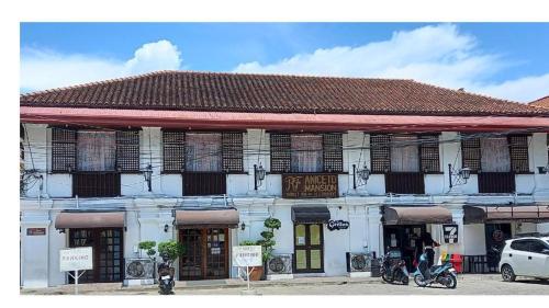 a white building with windows and motorcycles in front of it at RF ANICETO MANSION in Vigan