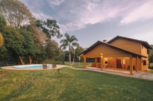 een klein huis met een zwembad in de tuin bij Casa de campo São Bartolomeu in Coronel Pilar
