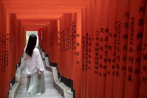 a woman walking through a row of red walls at OMO3 Tokyo Akasaka by Hoshino Resort in Tokyo
