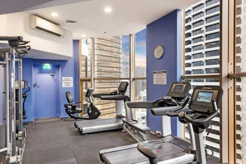 a gym with several tread machines and a blue wall at CBD Curated Comfort, Resort Style Living in Sydney
