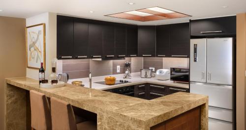 a kitchen with black cabinets and a marble counter top at Shanghai Centre Serviced Apartment in Shanghai
