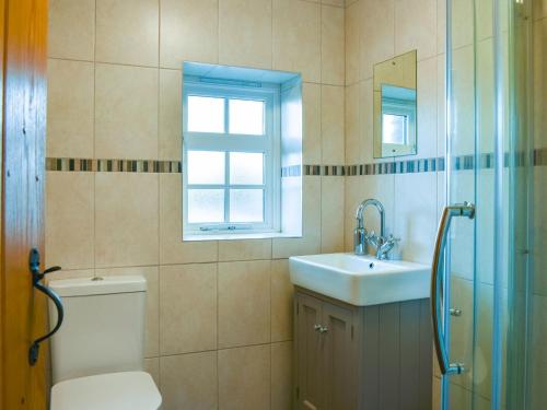 a bathroom with a toilet and a sink and a window at The Hayloft in Crosby Garrett