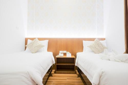 duas camas num quarto de hotel com uma mesa de cabeceira entre elas em King's Palace Mitra RedDoorz em Medan
