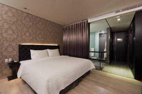 a bedroom with a large white bed and a bathroom at FX Hotel Taipei Nanjing East Road Branch in Taipei