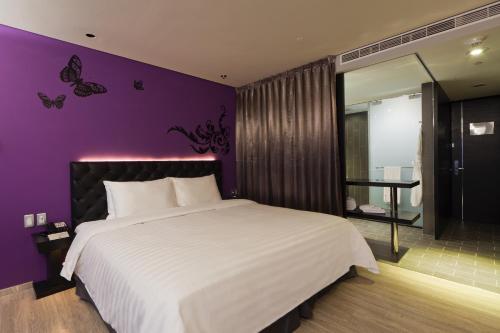 a bedroom with a large bed with a purple wall at FX Hotel Taipei Nanjing East Road Branch in Taipei