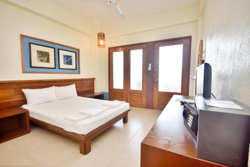 a bedroom with a bed and a flat screen tv at Agos Boracay Rooms + Beds in Boracay