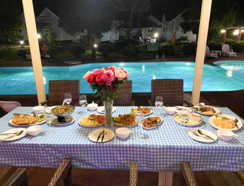 a table with plates of food next to a pool at Akantuka Homestay in Chanthaburi
