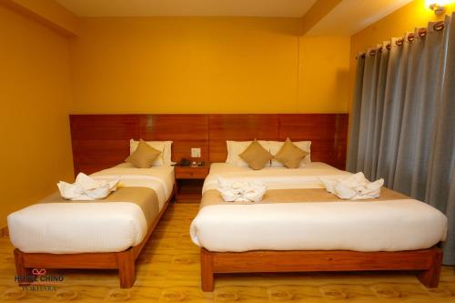 two beds in a room with yellow walls at Hotel Chino Pokhara in Pokhara