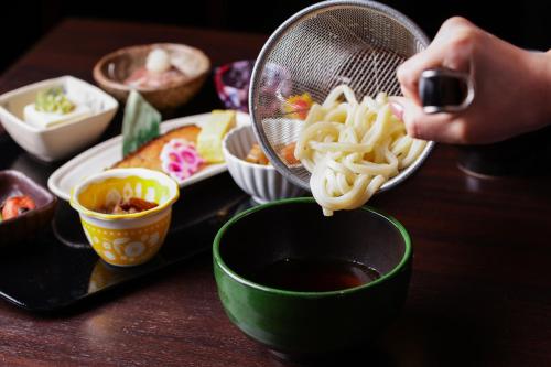 a person is cooking noodles in a strainer at HOTEL MYSTAYS Sakaisuji Honmachi in Osaka