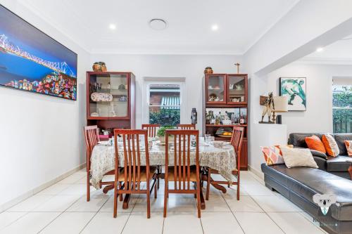 a dining room with a table and chairs and a couch at KozyGuru | Rockdale | Spacious Modern 2 Bedrooms Holiday Home in Sydney
