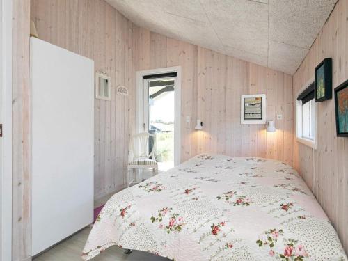 ein Schlafzimmer mit einem weißen Bett mit Blumen darauf in der Unterkunft Holiday home Blokhus XLII in Blokhus