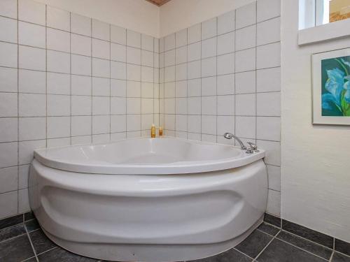 La salle de bains est pourvue d'une baignoire blanche et de carrelage blanc. dans l'établissement 6 person holiday home in Karreb ksminde, à Karrebæksminde