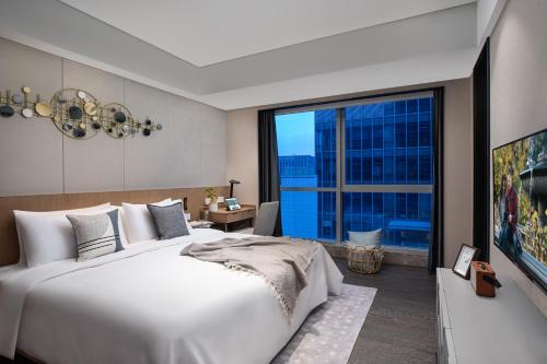 sypialnia z dużym białym łóżkiem i dużym oknem w obiekcie Citadines New District Wuxi w mieście Wuxi