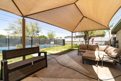a patio with two chairs and a couch under a large umbrella at Remodeld5BR Modern Retreat with Covered Pool in El Paso
