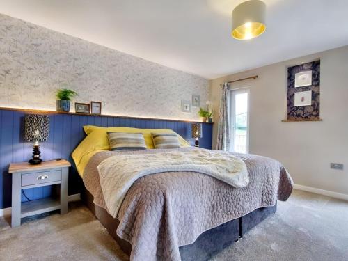 1 dormitorio con 1 cama con pared azul en Woodhouse Lodge, en Pooley Bridge