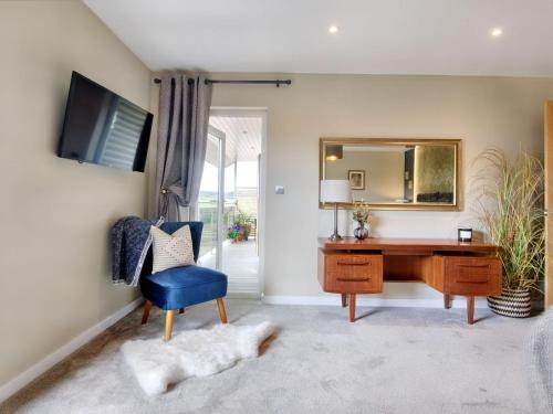 1 dormitorio con escritorio, silla azul y espejo en Woodhouse Lodge en Pooley Bridge