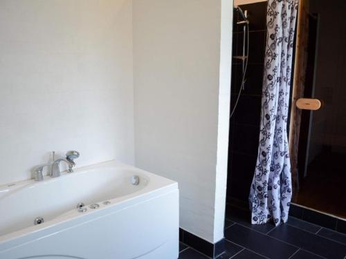 La salle de bains est pourvue d'une baignoire blanche et d'une douche. dans l'établissement Holiday home Brovst VIII, à Brovst
