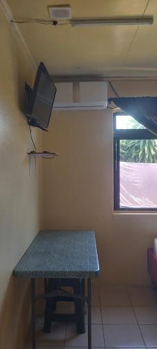 Habitación con mesa y TV en la pared. en Raihei Auberge de jeunesse Chez l'habitant à Bora Bora, en Bora Bora