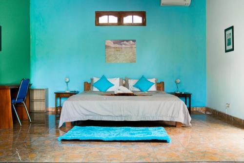 a blue bedroom with a bed with blue walls at Lovina Vibes Hotel in Balian