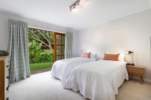 two beds in a white room with a window at Peace-Realm Retreat in Matakana