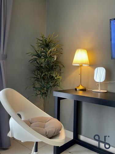 a white chair sitting next to a desk with a lamp at Homesuite' Home at Aeropod SOVO in Kota Kinabalu