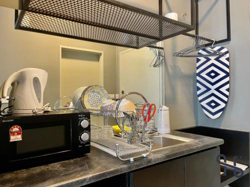 a kitchen counter with a sink and a microwave at Homesuite' Home at Aeropod SOVO in Kota Kinabalu