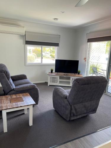 a living room with two chairs and a flat screen tv at Busselton Jetty Chalets in Busselton