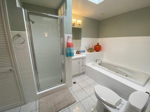 y baño con ducha, aseo y bañera. en Charming Duplex with private backyard en Los Ángeles